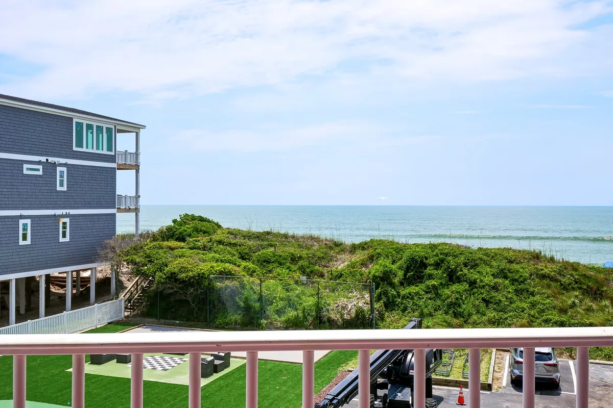 A serene view from the dining area or deck, looking out over the ocean with greenery and a balcony railing in the foreground. The space offers a peaceful backdrop for al fresco dining, with opportunities to enjoy sunrise or sunset meals.