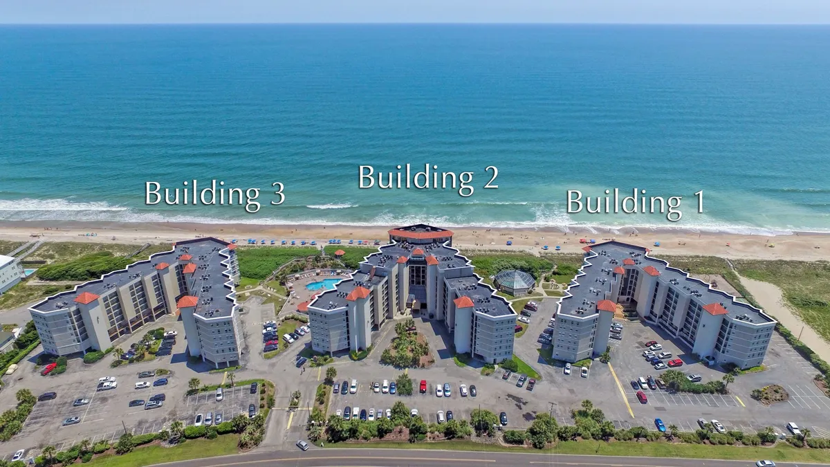 This exterior image captures three resort buildings with a large swimming pool in the foreground and the ocean visible beyond. The inviting pool area, expansive view, and proximity to the shoreline emphasize the property's resort atmosphere and direct beach access.
