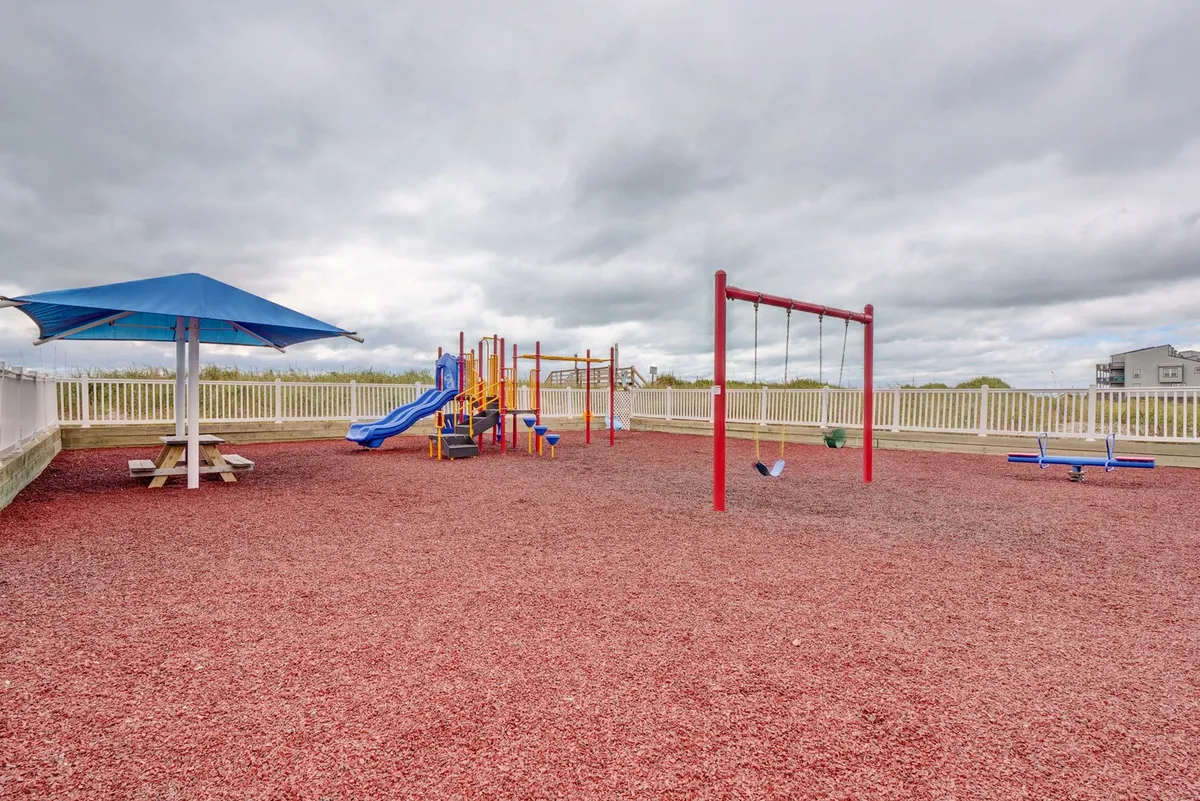 A lively playground with modern swings and play structures set atop a safety surface, flanked by picnic areas that invite family gatherings and community fun.