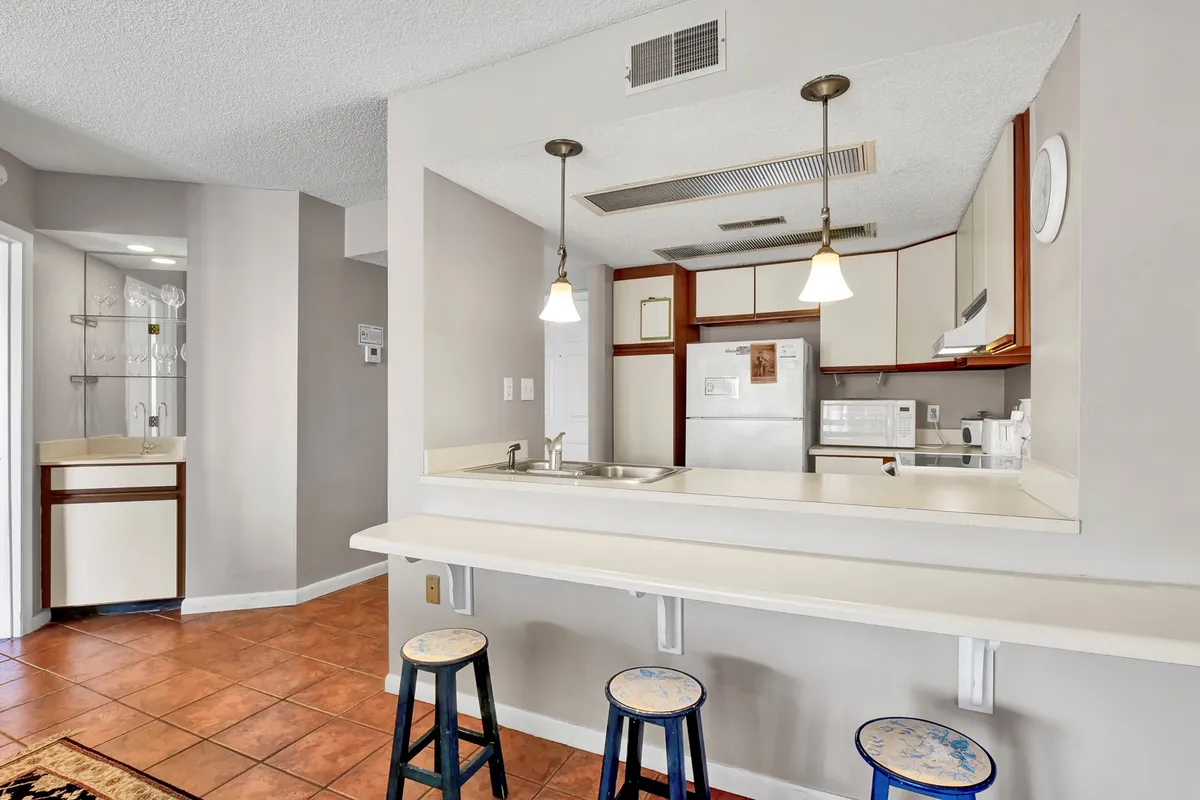 This image showcases a bright, modern kitchen with a spacious breakfast bar, sleek kitchen appliances, and comfortable stools. The setup is ideal for casual dining, meal prep, and socializing, reflecting a relaxed yet functional atmosphere. The lighting and layout invite group gatherings and shared moments.